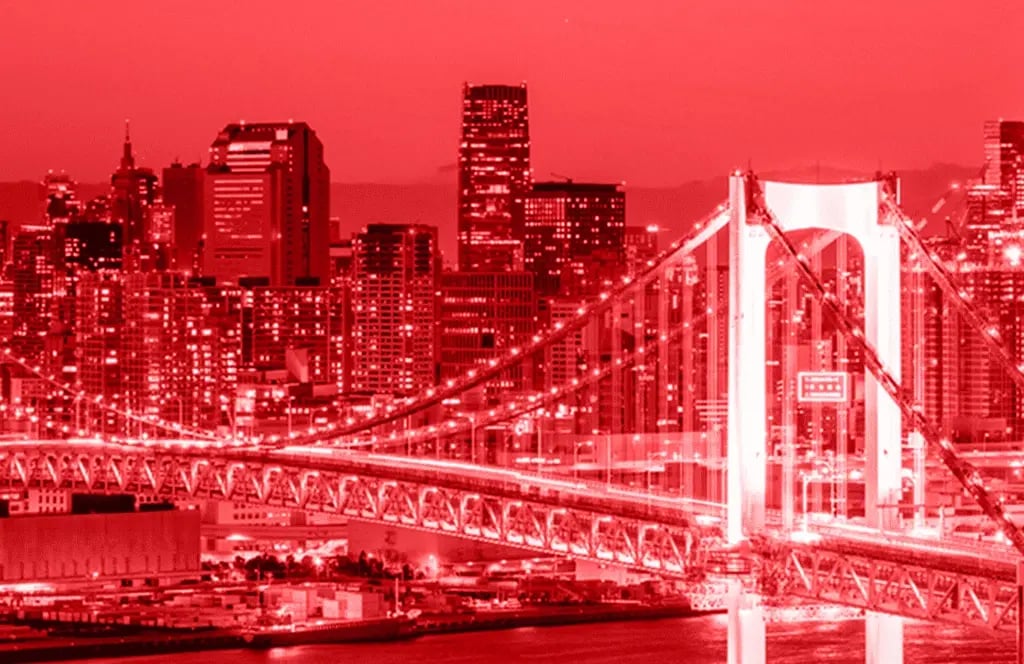 Panorama einer japanischen Metropole bei Nacht mit beleuchteten Hochhäusern und einer großen Brücke im Vordergrund.