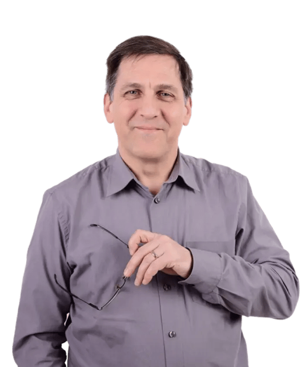 Holger Dietz, an employee of RIEDEL Networks, stands in front of a white background. He is wearing a long-sleeved, gray shirt with a button placket.